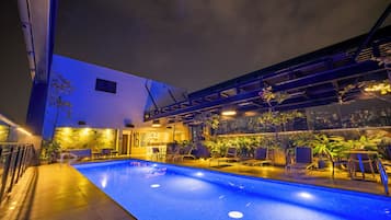 Una piscina al aire libre, sombrillas, sillones reclinables de piscina