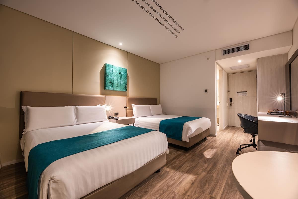 Habitación de hotel con dos camas, un escritorio y una silla.