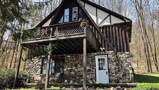 Un chalet rustique avec une façade en pierre, un balcon en bois et une entrée en pierre.