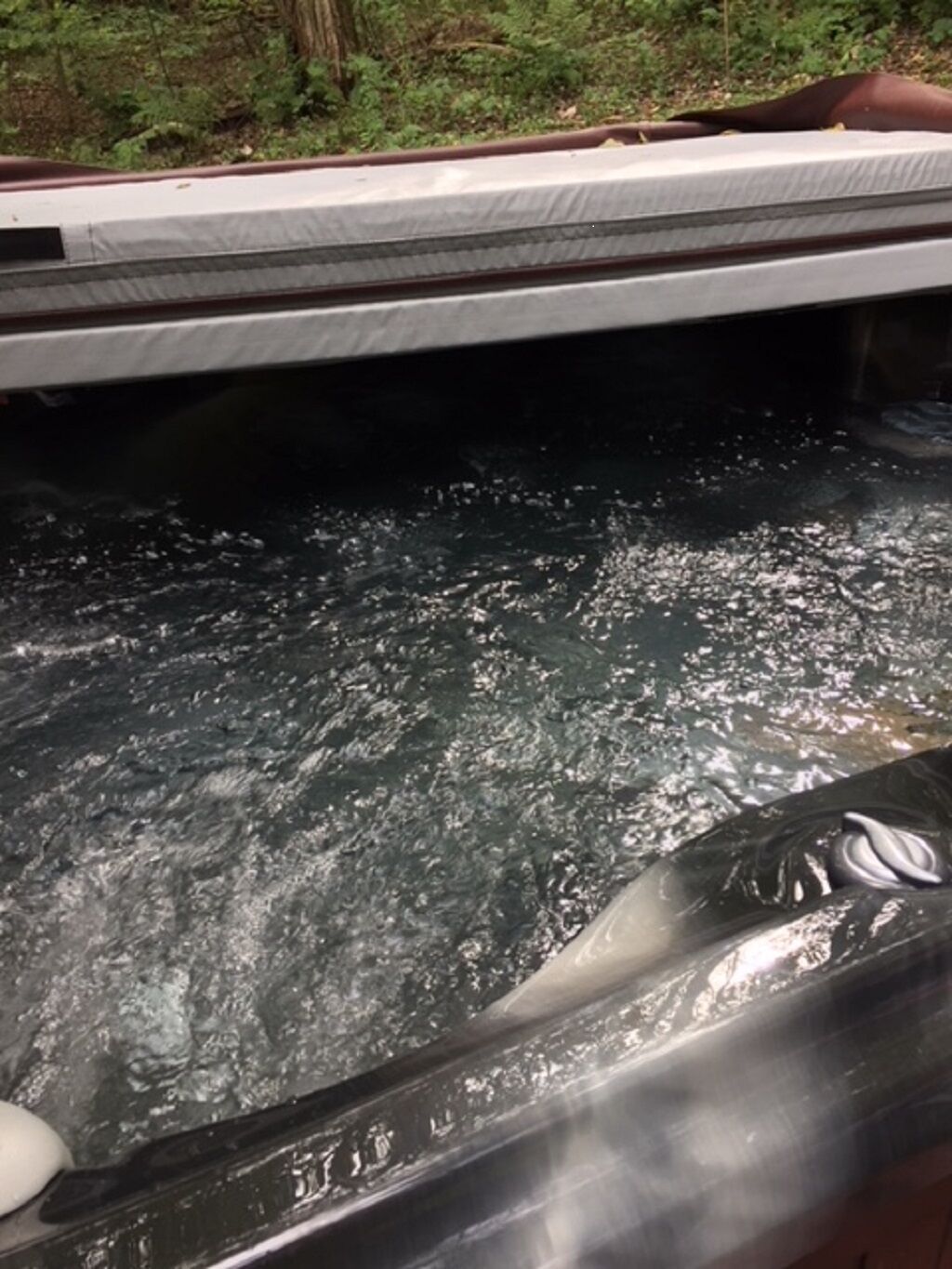 A hot tub with a visible water pump and a control panel.