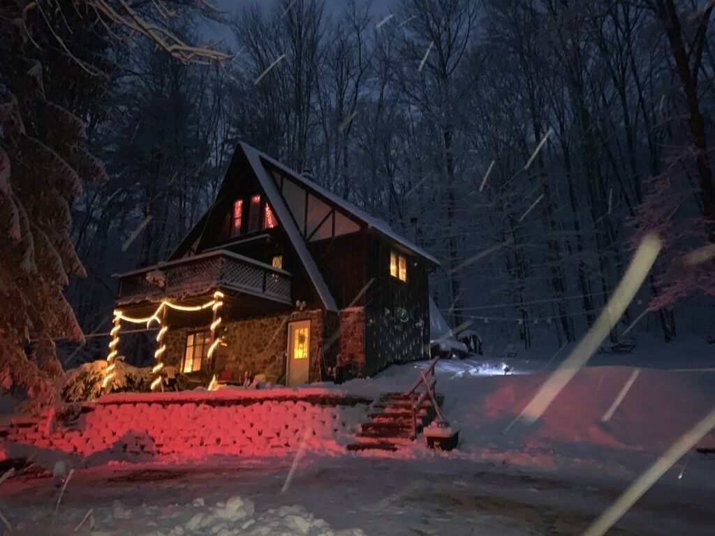 A cabin with a stone exterior, a sloped roof, and a wooden staircase leading to the entrance.