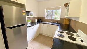 Een kleine keuken met een koelkast, magnetron, kookplaat en spoelbak.