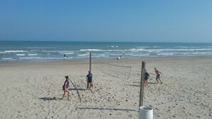 A beach volleyball court with players and a net, set against a clear sky and ocean view. - Beachfront Condo directly on the Beach -1st Floor; Newly Remodeled (South Padre Island)