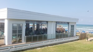 A modern building with large windows overlooking the beach. - Beachfront Condo directly on the Beach -1st Floor; Newly Remodeled (South Padre Island)
