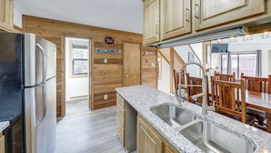 A kitchen with wooden cabinets, a stainless steel refrigerator, granite countertops, and a sink. - Angel Fire Resort Condo, 400 Feet to Chile Express (Angel Fire)