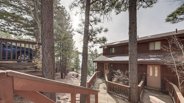 A wooden deck leading to a building surrounded by tall pine trees. - Angel Fire Resort Condo, 400 Feet to Chile Express (Angel Fire)
