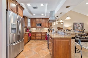 A modern kitchen with wooden cabinets, stainless steel appliances, and a central island.