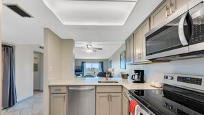 Eine moderne Küche mit Spülmaschine, Mikrowelle, Herd und Deckenventilator.