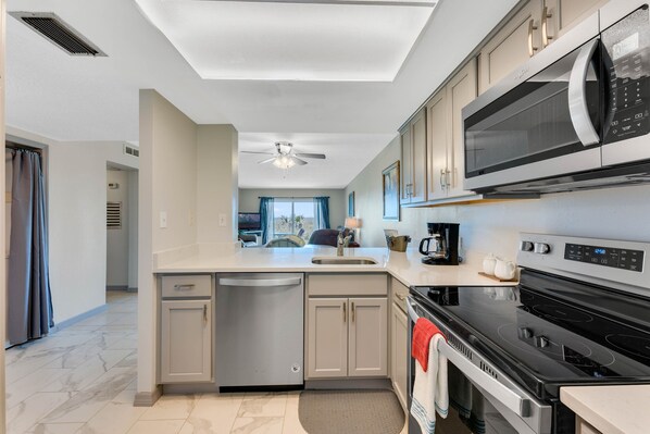 A modern kitchen with a dishwasher, microwave, stove, and a ceiling fan.