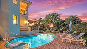 A swimming pool with lounge chairs and a building with a balcony. - The Sun Dial | Waterfront Home on Siesta Key w/ Private Pool & Large Backyard, Close to Beach! (Siesta Key)