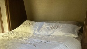 A bed with a white quilt and floral embroidery, a wooden headboard, and a carpeted floor. - Best price, clean and new rv  trailer  (Los Angeles)