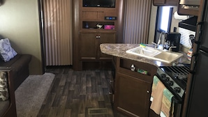 A compact RV kitchen with a built-in oven, microwave, and sink. - Best price, clean and new rv  trailer  (Los Angeles)