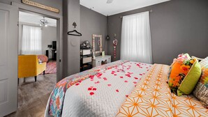 A bedroom with a bed, a ceiling fan, a dresser, a mirror, and a door leading to another room. - Private Guest House-Hermann MO (Hermann)