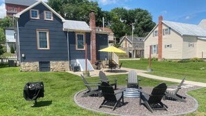 A backyard with a circular seating area, a grill, and a yellow umbrella. - Private Guest House-Hermann MO (Hermann)