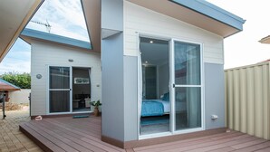 A modern house with a patio, a sliding glass door leading to a bedroom, and a small outdoor kitchen area. - Prestigious Northshore Guest House - Comfortable Living Close To Mullaloo Beach (Kallaroo)