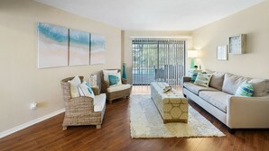 A living room with a sofa, two armchairs, a coffee table, and artwork on the wall. - Villa Tara: Gulf-Access, Heated Pool, Private Dock (Cape Coral)