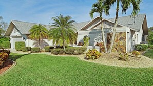 A two-story house with a well-maintained lawn, palm trees, and a stone facade. - Villa Tara: Gulf-Access, Heated Pool, Private Dock (Cape Coral)