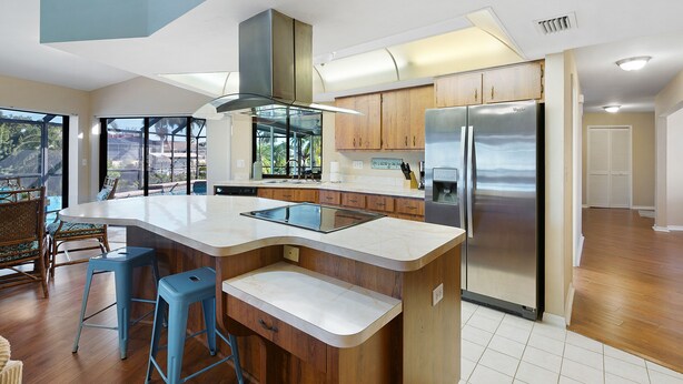 A modern kitchen with a large island, stainless steel appliances, and wooden cabinets. - Villa Tara: Gulf-Access, Heated Pool, Private Dock (Cape Coral)