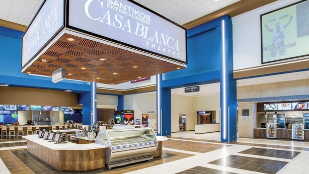 Un hall d’entrée spacieux avec un présentoir central de glaces, une enseigne indiquant le « Casa Blanca Theatre » et un panneau indiquant « 15 minutes en voiture ».