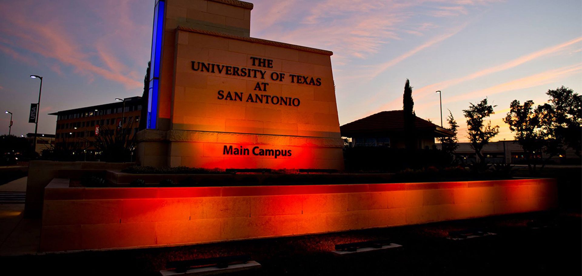 The University of Texas at San Antonio main campus sign illuminated at dusk.