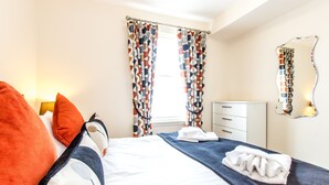 A hotel room with a bed, pillows, a bedside table, a dresser, and a mirror. - Under Edinburgh Castle (Edinburgh)