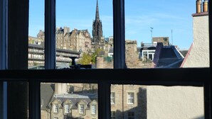 A view through a window of a building with multiple windows, a stone facade, and a clear sky. - Under Edinburgh Castle (Edinburgh)