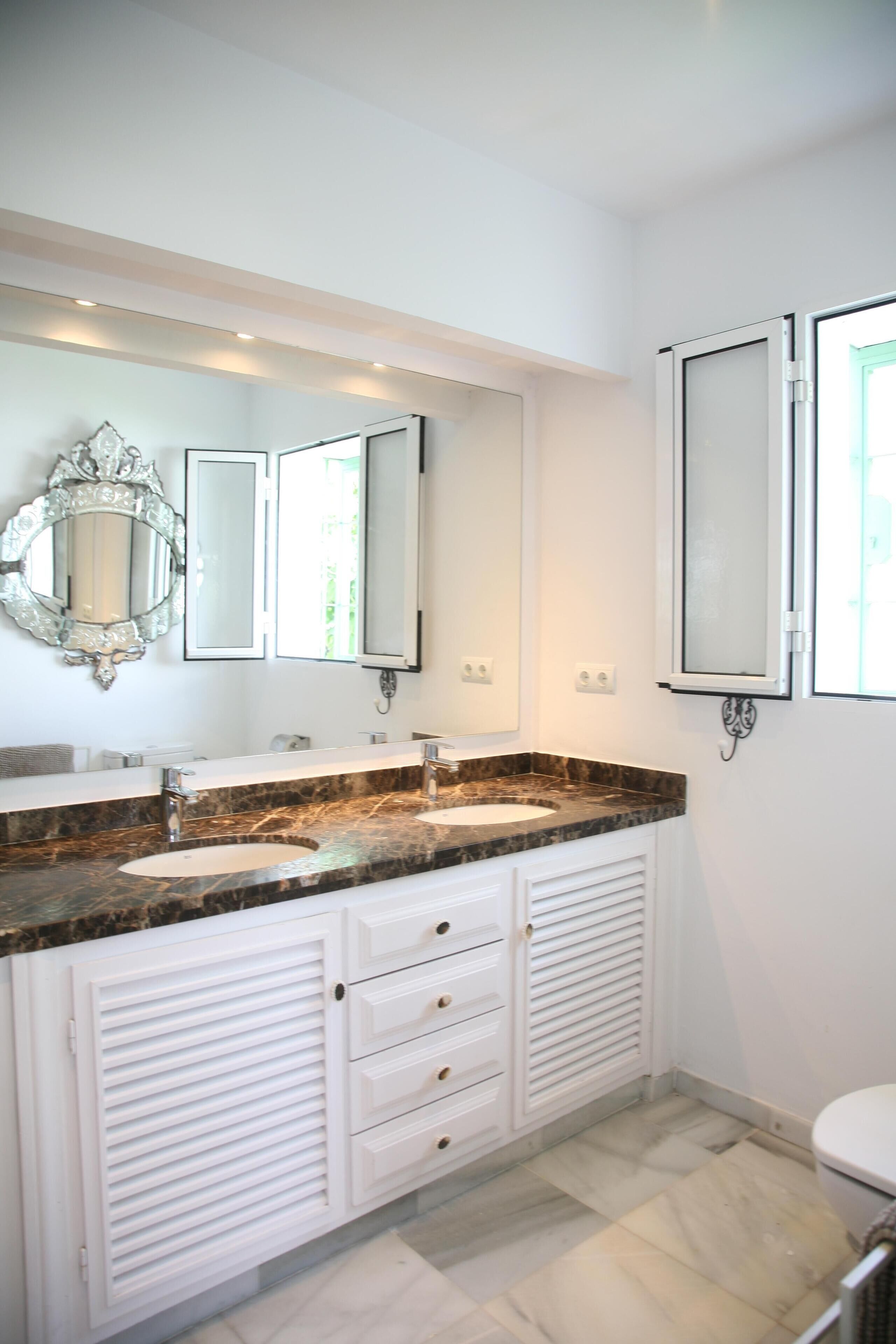 Une salle de bain moderne avec deux lavabos, un grand miroir et des toilettes.