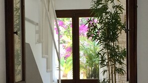 A hallway leading to a staircase with a wooden door and a potted plant.