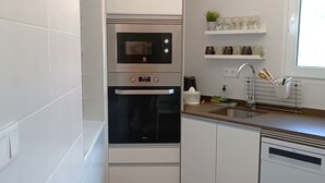 Eine kleine Küche mit weißen Schränken, einem Backofen und einem Geschirrspüler.