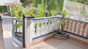 Ein Balkon mit Fliesenboden, weißer Brüstung und Topfpflanzen.