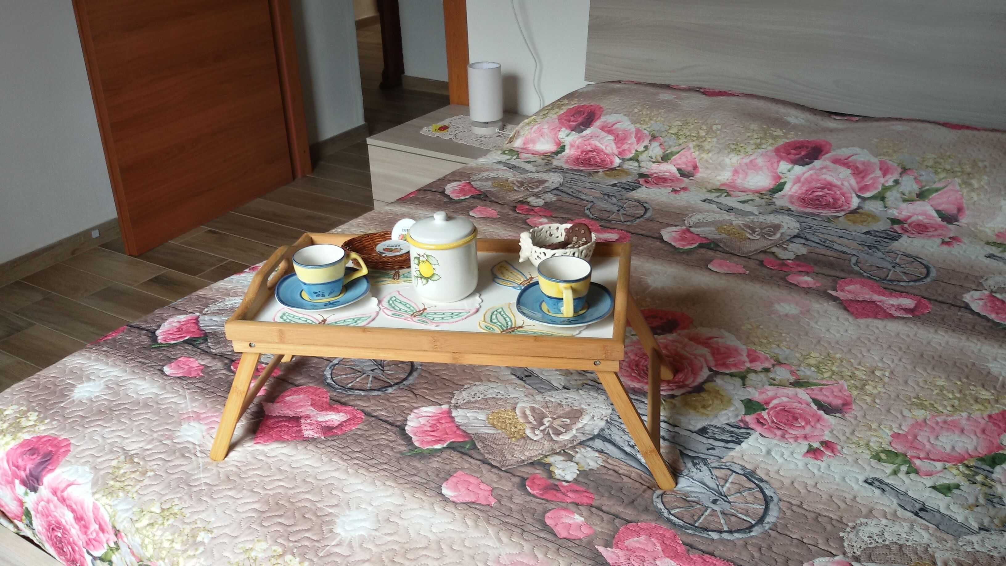 Ein hölzernes Tablett mit Tee-Service auf einer blumigen Tagesdecke.