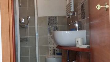 Ein kleines Badezimmer mit Dusche, Toilette und Waschbecken.
