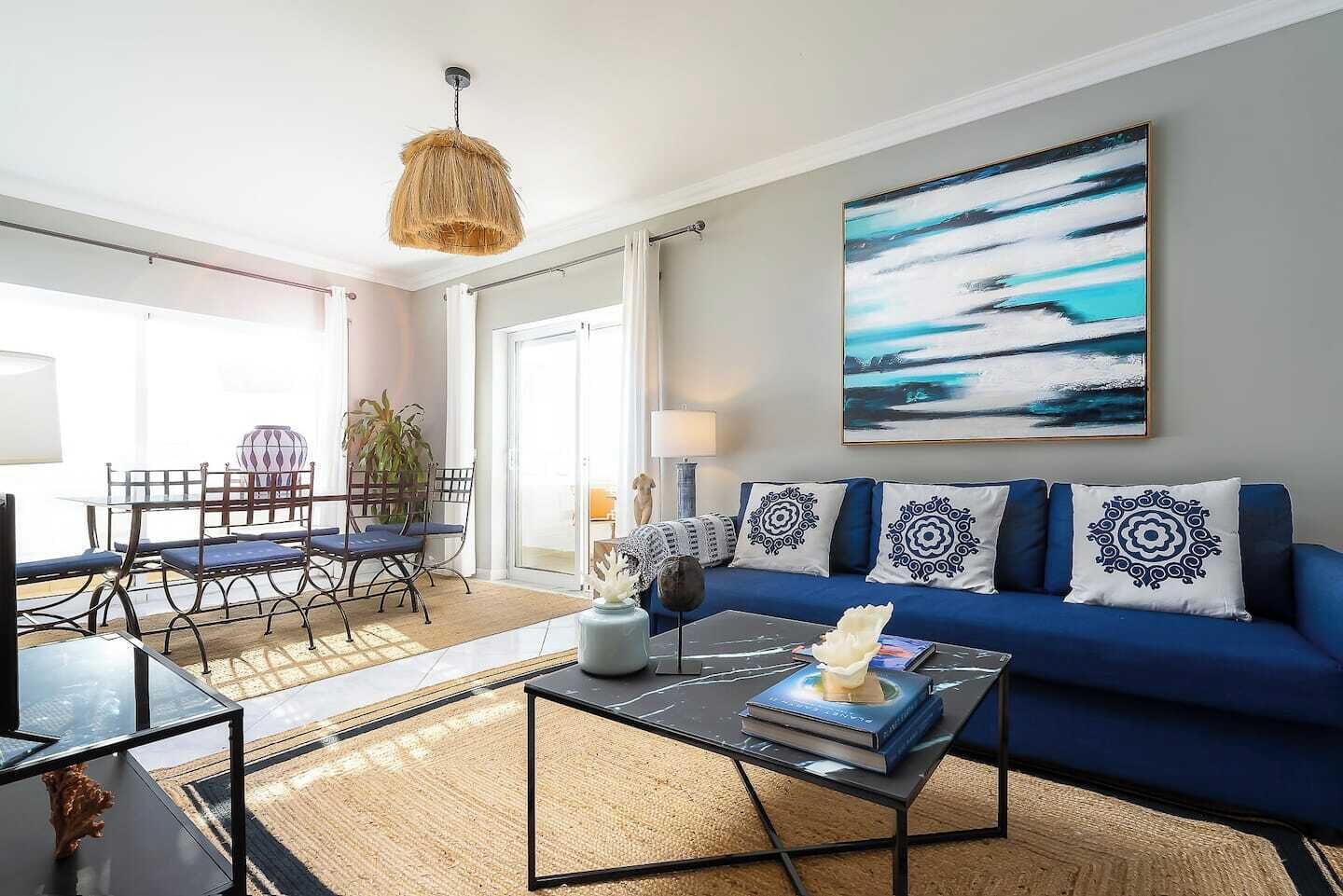 Ein modernes Wohnzimmer mit einem blauen Sofa, einem Couchtisch und einem Essbereich mit Tisch und Stühlen.