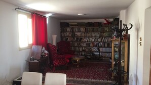 A room with a dining table, chairs, a bookshelf, a red armchair, and a patterned rug. - Apartment with a prefect sea view  (Stanly)