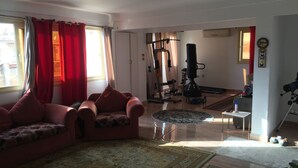 A living room with a sofa, a coffee table, and a rug. There is a door leading to another room with exercise equipment. - Apartment with a prefect sea view  (Stanly)