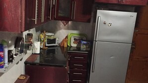 A compact kitchen with wooden cabinets, a stainless steel refrigerator, a microwave, and a small countertop. - Apartment with a prefect sea view  (Stanly)