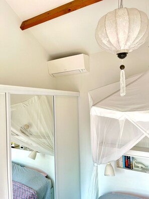 Un dormitorio con cama con dosel, ventilador de techo y estantería.