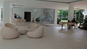 Een ruime lobby met modern wit meubilair, waaronder zitplaatsen en een eetgedeelte.