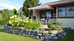 Une maison avec un jardin de pierres, une terrasse avec des chaises et un espace extérieur aménagé et abrité.