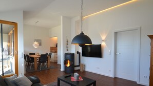 Een moderne woonkamer met een open haard, een eethoek en een aan de muur bevestigde televisie.