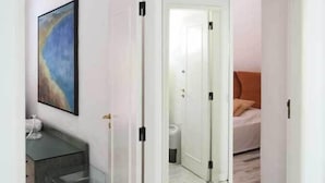 Hotellihuone, jossa on marmorilattia, oranssilla tekstiilillä varustettu sänky ja seinällä taulu.