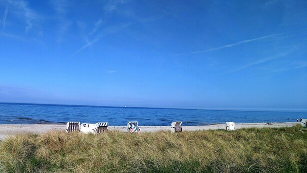 A beach with a clear view of the ocean, a sandy path leading to the water, and several beach chairs and umbrellas. - Lykkelig Ferie: bright apartment, south-facing balcony, beach 30 m, indoor pool, IR cabin, sauna (Kronsgaard)