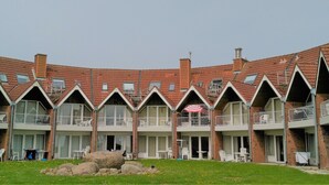 A multi-story building with a brick facade, multiple balconies, and large windows. - Lykkelig Ferie: bright apartment, south-facing balcony, beach 30 m, indoor pool, IR cabin, sauna (Kronsgaard)