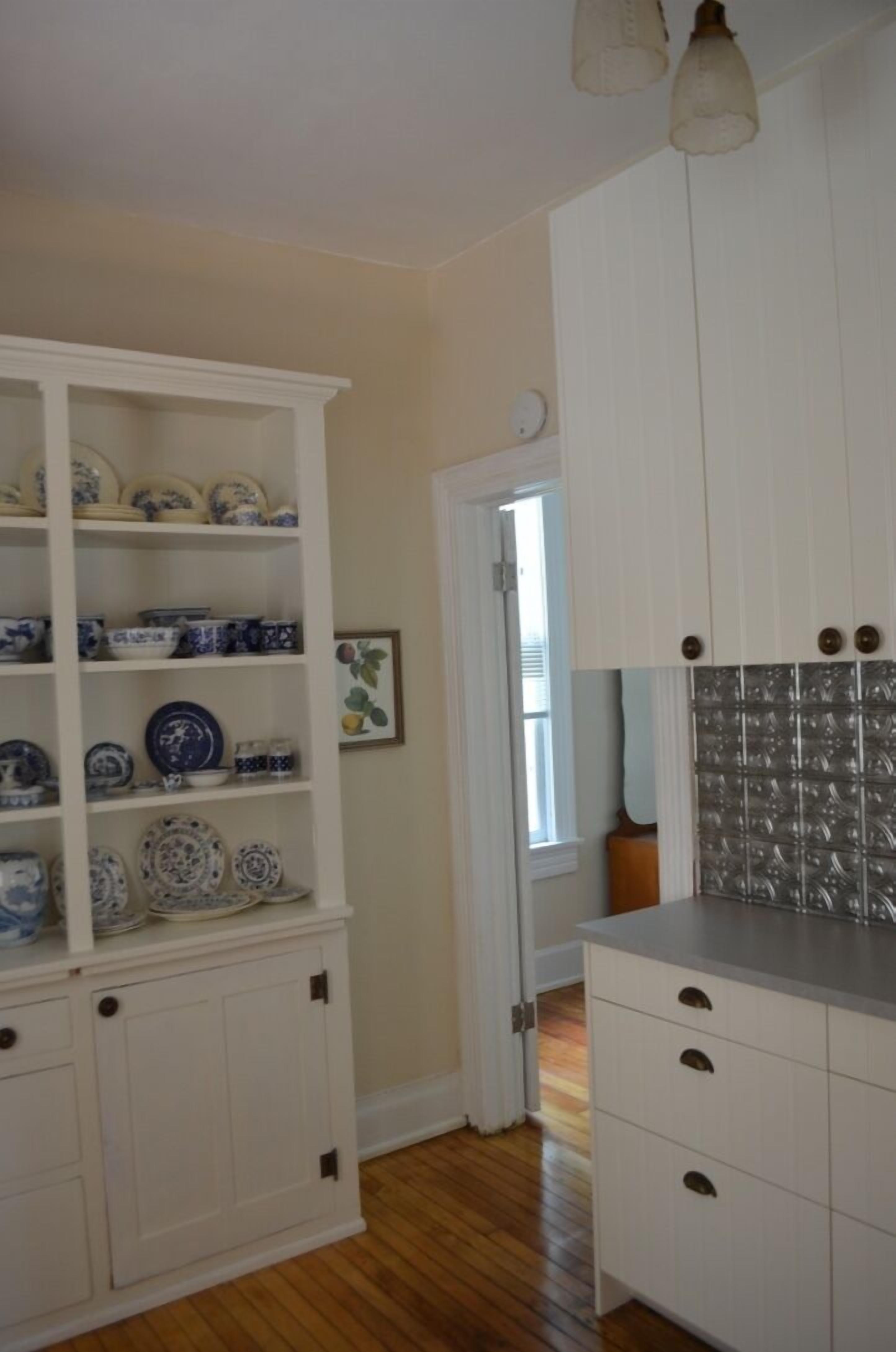 Una cocina con armarios blancos, un escurreplatos azul y blanco, y un salpicadero de azulejos.