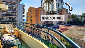 A balcony with outdoor furniture, a view of the cityscape, and the Negresco Hotel building in the background.