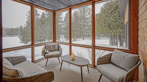 Une pièce chaleureuse avec de grandes fenêtres, des meubles en osier et une vue sur un paysage enneigé.