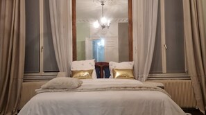 Ein Schlafzimmer mit einem großen Bett, einem Spiegel und Vorhängen.