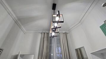 A room with a modern chandelier, a window with curtains, and a door.