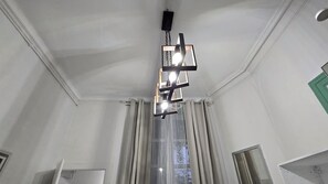 Een kamer met een moderne kroonluchter, een raam met gordijnen en een deur.