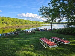 Ein Picknickplatz am Seeufer mit Bänken, Picknicktischen und Liegestühlen.